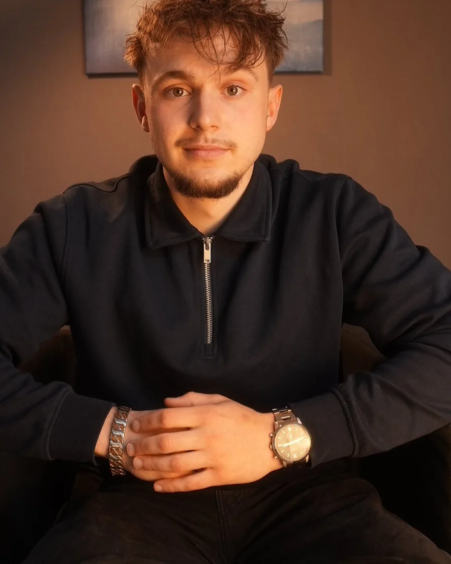 Paul Kürbis, Webdesigner aus Wildeshausen, sitzend im dunklen Half-Zip-Pullover in seinem Arbeitszimmer